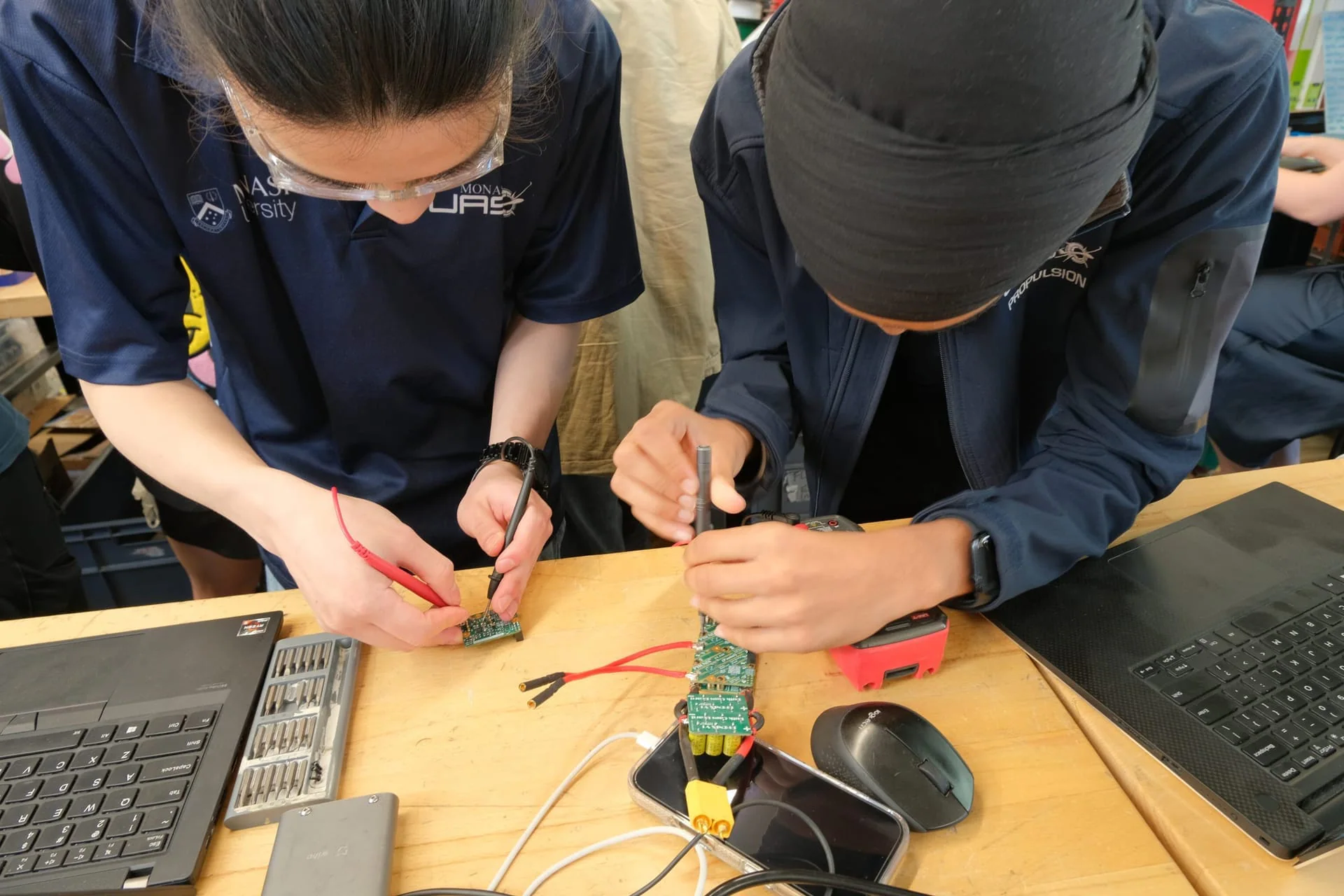 Propulsion members working on electronics at a bench